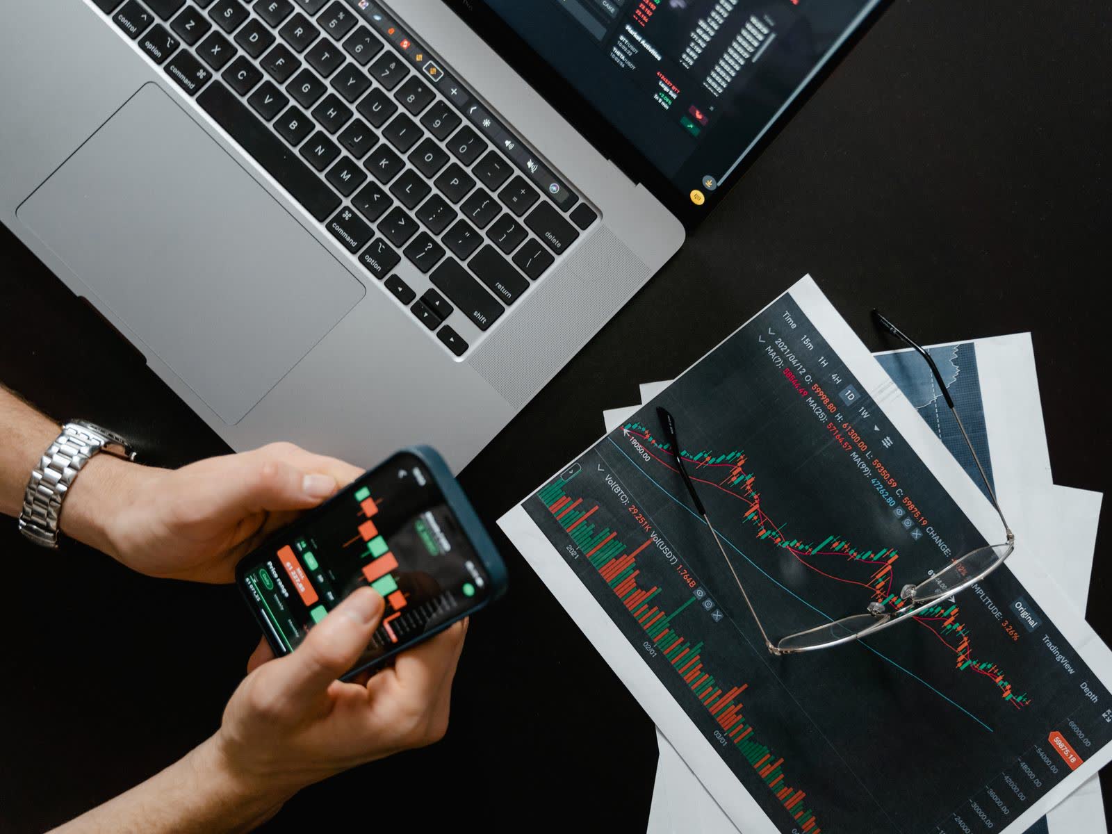 Bureau sombre avec des graphiques financiers et des écrans de trading en direct